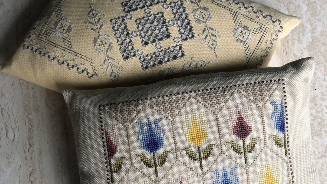 To broderte puter på marmorflate; den øverste puten har et geometrisk mønster, mens den nederste har et blomsterdesign med blå, gule og røde tulipaner, som minner om skatter som ble oppdaget på et loppemarked.