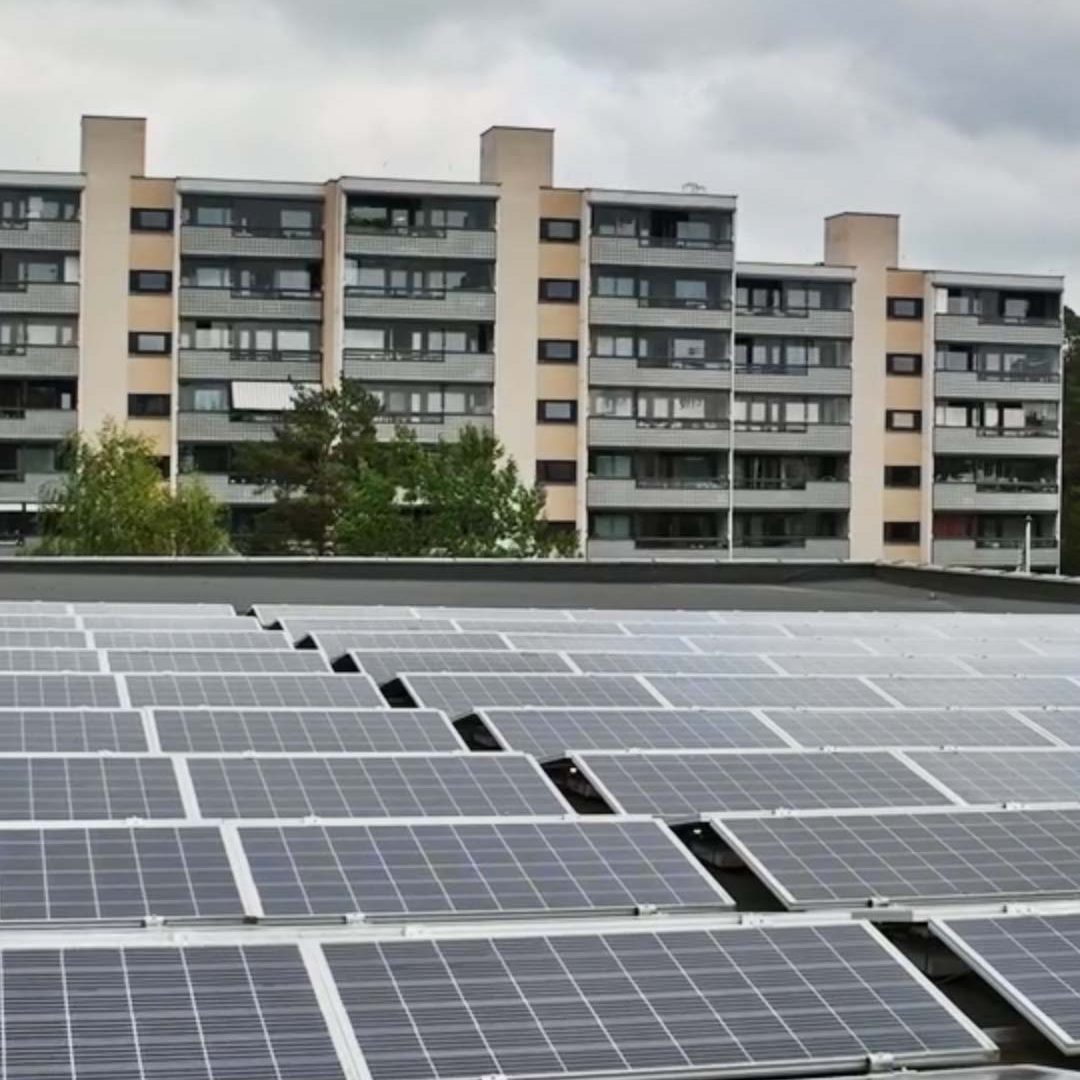 Solcellepaneler på et hustak med leilighetsbygg i bakgrunnen, viser Oslos satsing på bærekraft gjennom KlimaOslo-tiltak under overskyet himmel.