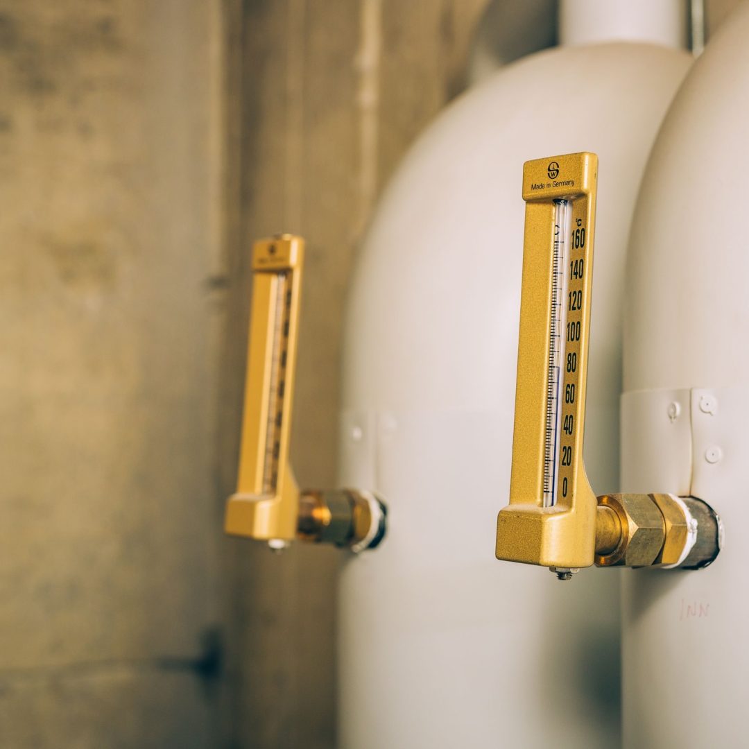 I et rom med beige vegger er to industrielle trykkmålere dyktig festet til store sylindriske tanker, som viser presist isoleringsarbeid.