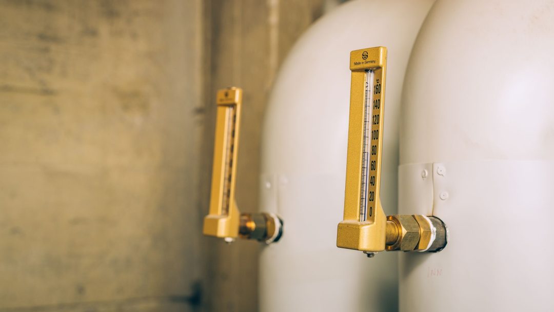 I et rom med beige vegger er to industrielle trykkmålere dyktig festet til store sylindriske tanker, som viser presist isoleringsarbeid.