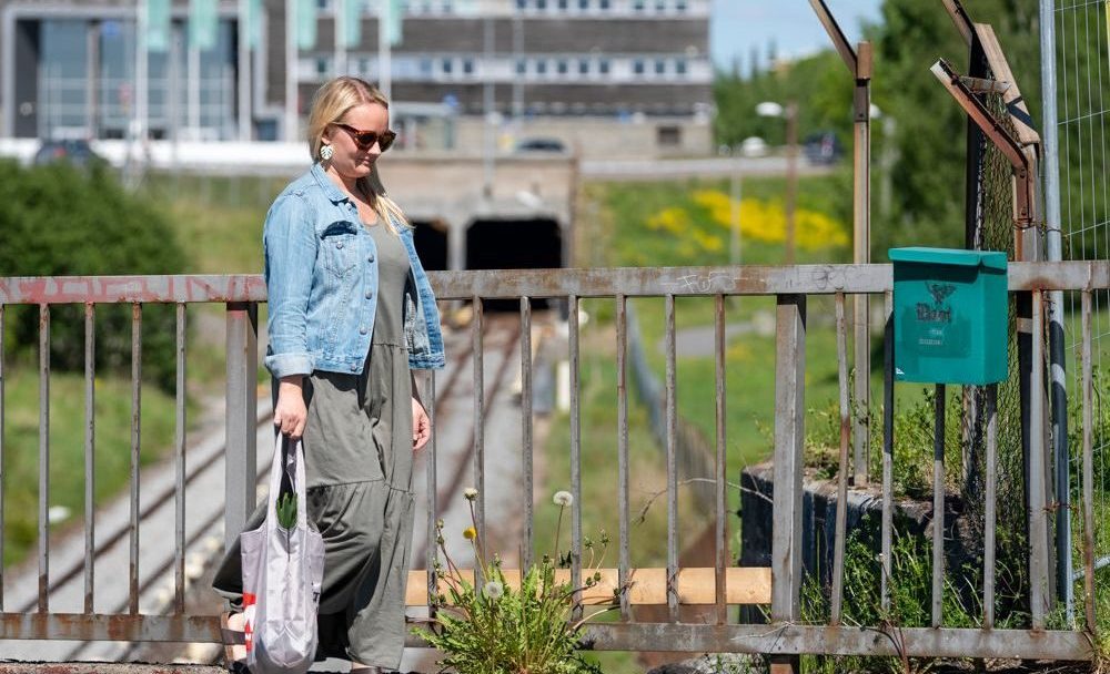 kvinne med bærenett går over en bro