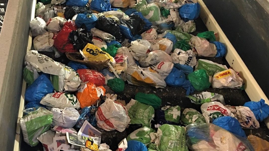 Diverse plastposer fylt med avfall beveger seg jevnt og trutt på et løpende bånd på gjenvinningsanlegget, og bidrar til et forbedret klimagassregnskap etter hvert som de behandles for gjenbruk.