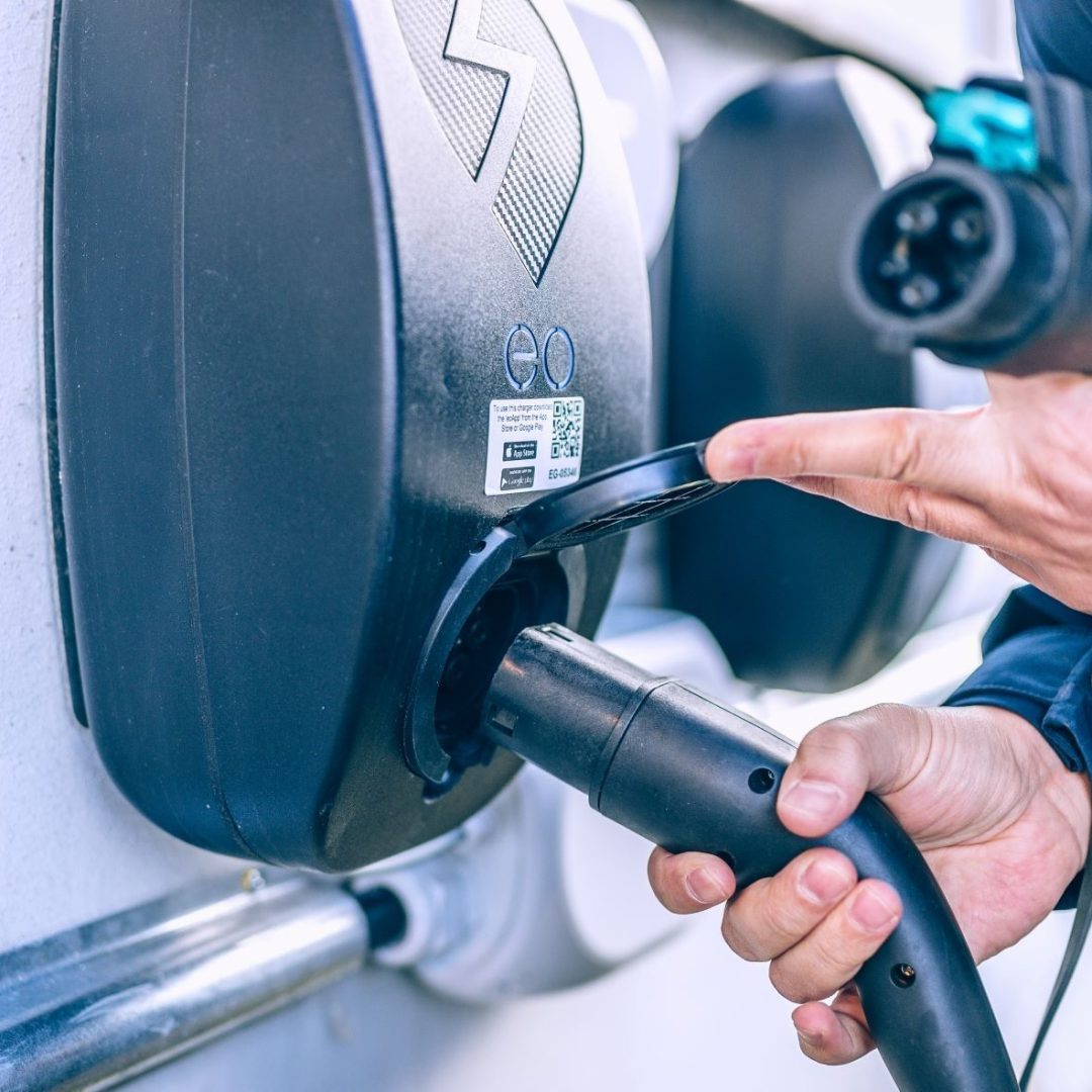 En person kobler en ladekabel for elektriske kjøretøy til en ladestasjon, og viser frem et viktig skritt i å støtte bærekraftig borettslag med moderne ladeinfrastruktur.