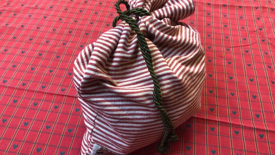 En grønn og hvit stripete veske på en rød og hvit rutete duk.