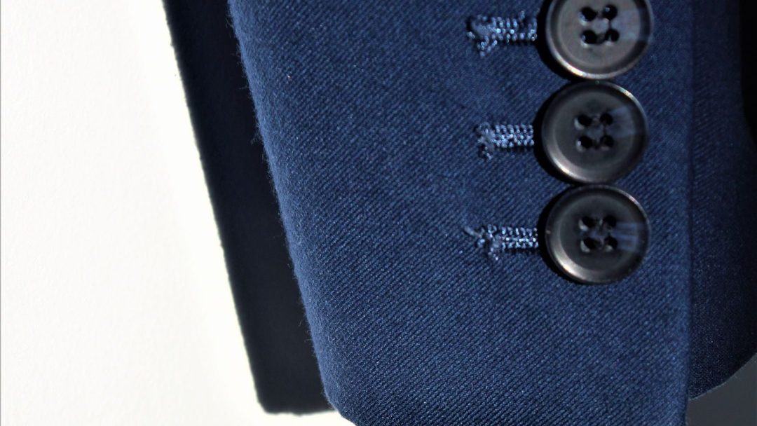 Nærbilde av Julen blå dresserme med tre sorte knapper elegant sydd langs mansjetten.