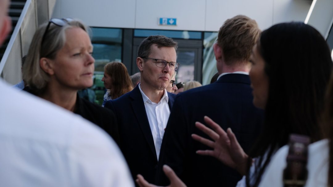 En gruppe mennesker i forretningsantrekk snakket utenfor en moderne bygning.