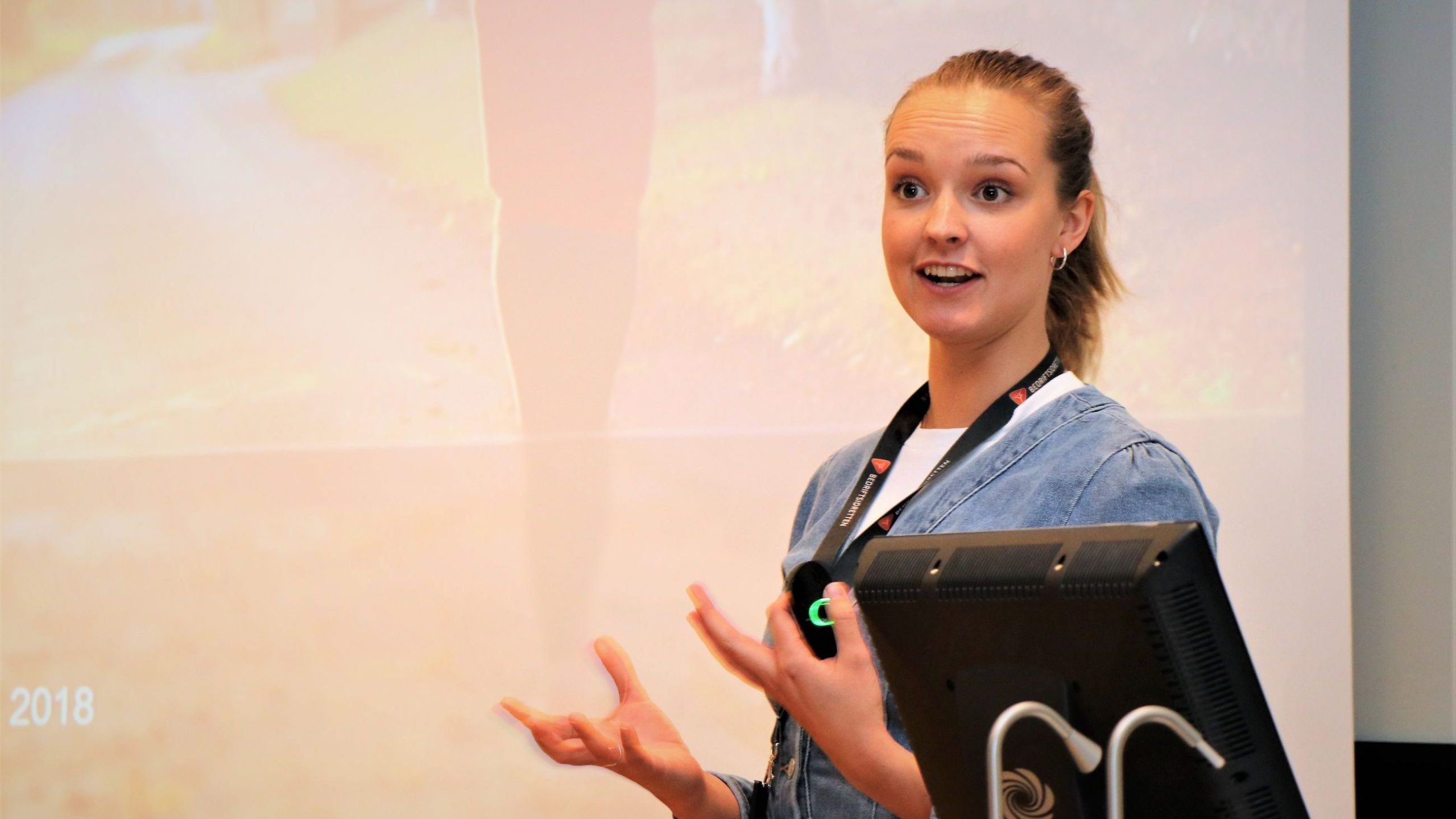 Person som står og snakker foran en skjerm, gestikulerer med hendene.