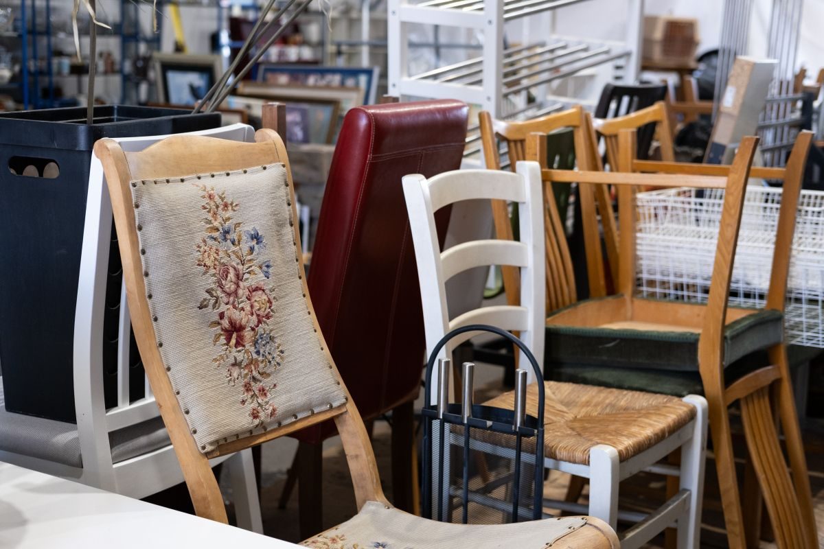 En rekke stoler, tilgjengelig for leie, i forskjellige stiler og materialer er stablet tett sammen i en lagrings- eller butikkplass.