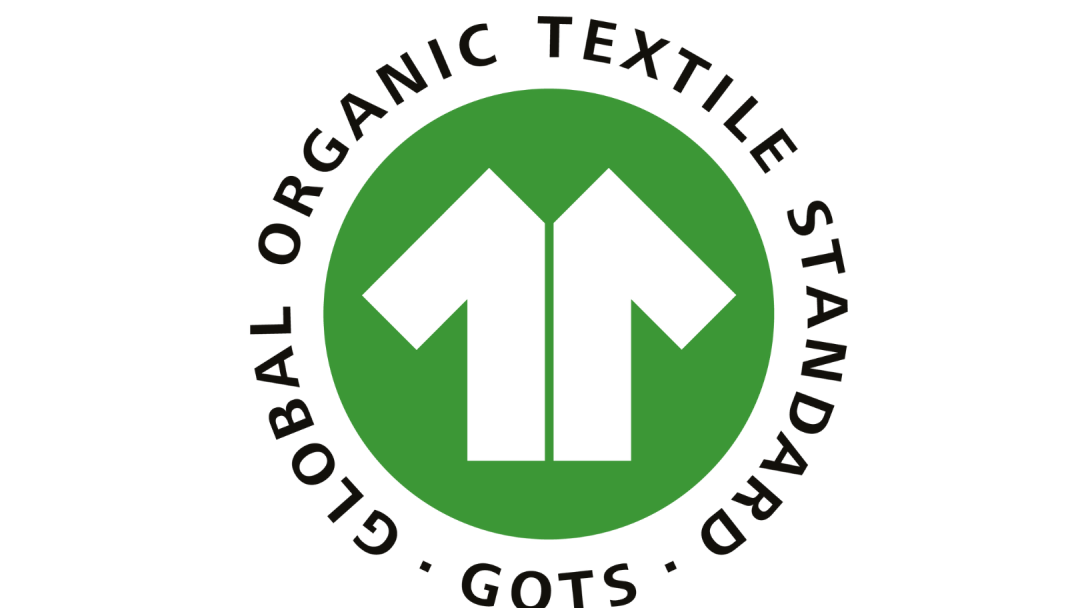 GOTS-logo med en grønn sirkel som inneholder et hvitt skjorteikon. Teksten lyder Global Organic Textile Standard - GOTS.