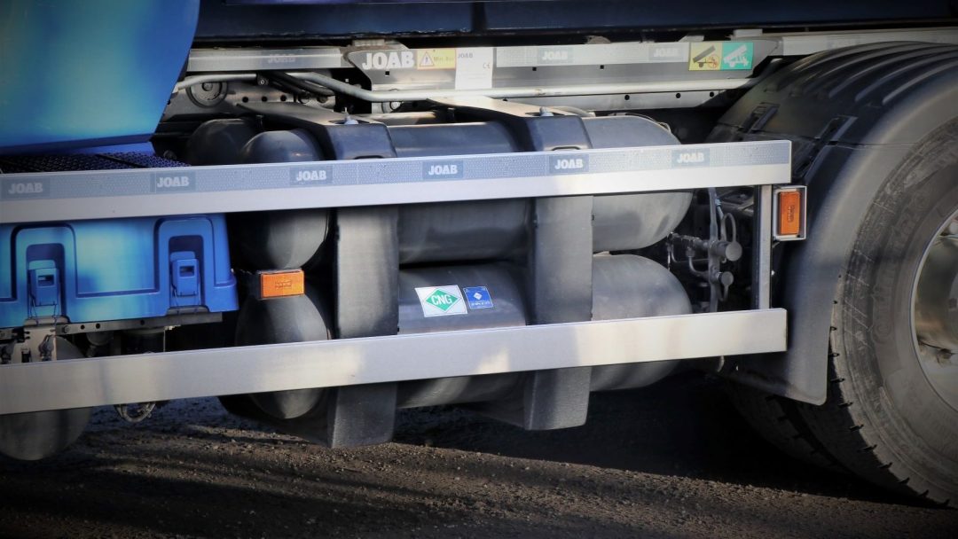 Nærbilde av en lastebils side, som viser drivstofftanker og en Nox-etikett. Lastebilen er blå med synlig bakhjul.