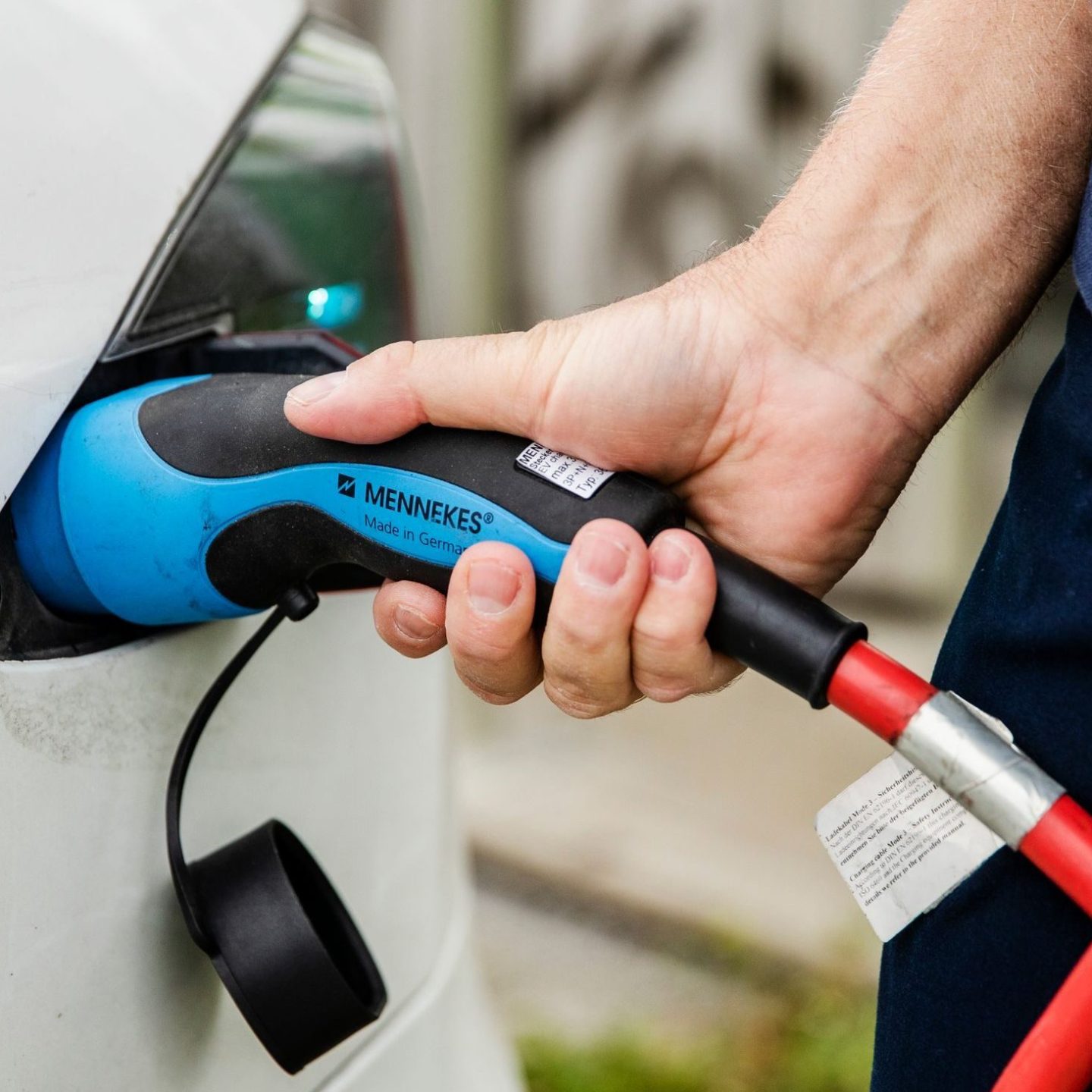 En person kobler en ladekabel til en elbiler, og setter scenen for en sømløs elektrisk reise.