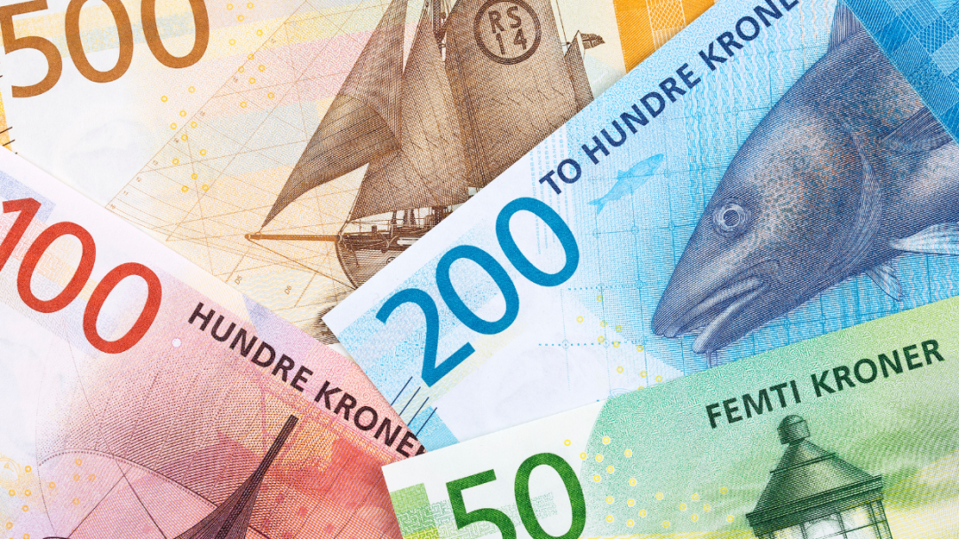 Nærbilde av norske sedler: 500, 200, 100 og 50 kroner, med design av skip, en fisk og et fyrtårn.
