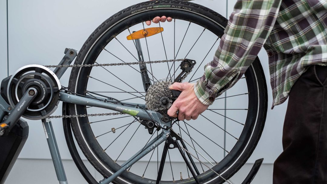 En person ekspert skifte dekk på et sykkelhjul i sitt innendørs stasjonære sykkeloppsett.