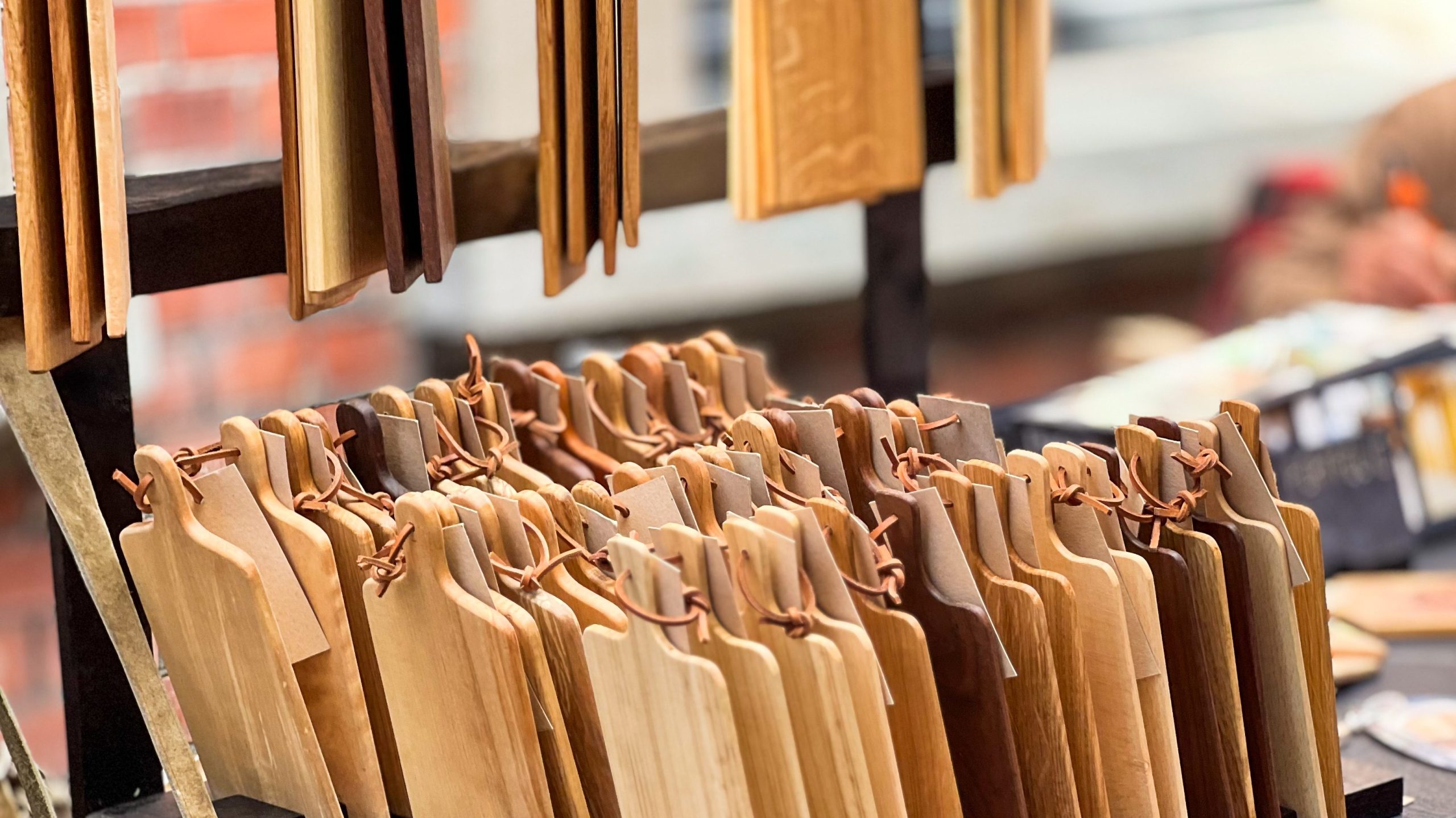 Et skattejakt av skjærebrett i tre med håndtak, hengende og stablet i rader, viser varierte nyanser og åremønstre.