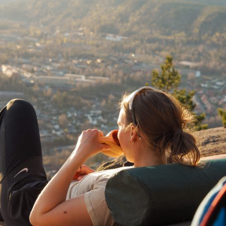 Slapp av i en åsside, lene deg tilbake på en pålitelig telt-ryggsekk, nyt en sandwich og nyt den naturskjønne utsikten over byen som ligger blant skogkledde åser.