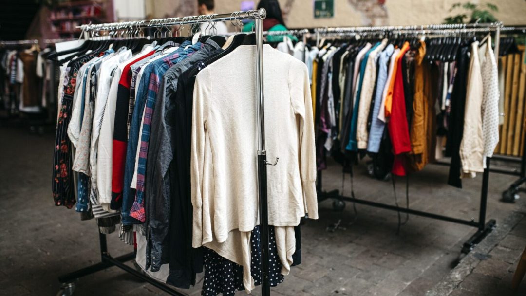 Utendørs henger stativer med assorterte klær fra Klager på klesstang av metall, og viser vakkert ulike stiler og farger.