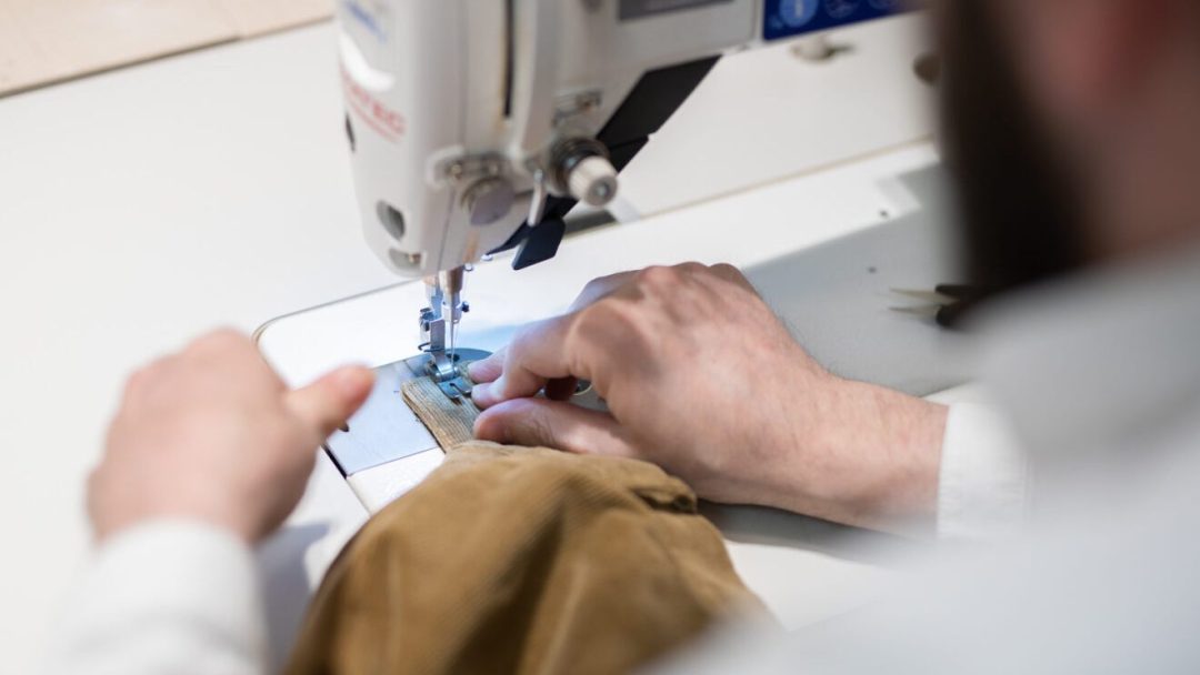 En Klager-syentusiast betjener en symaskin på en dyktig måte, og syr forsiktig en søm med presisjon og fokus.