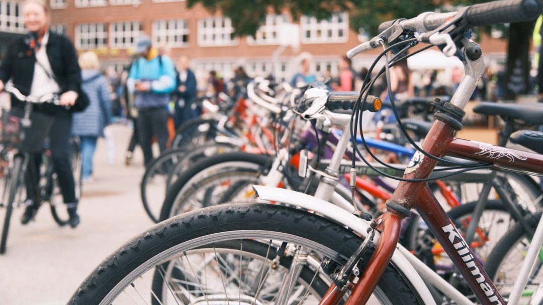 Nærbilde av sykkelhjul perfekt på linje foran en yrende folkemengde nær en bygning.