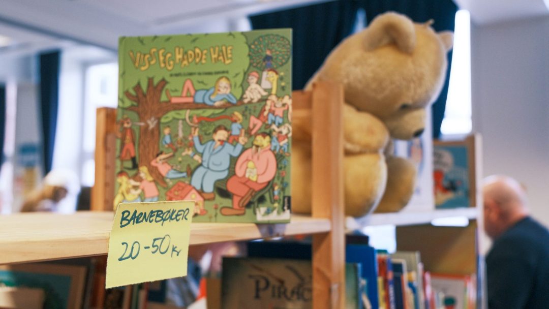 En sjarmerende barnebok og kosebamse står på en hylle i bokhandelen med hver sin prislapp Barnebøker 20-50 kr. Det er som om de har blitt oppdaget på et herlig loppemarked, og venter på at små hender skal gi dem nye eventyr.