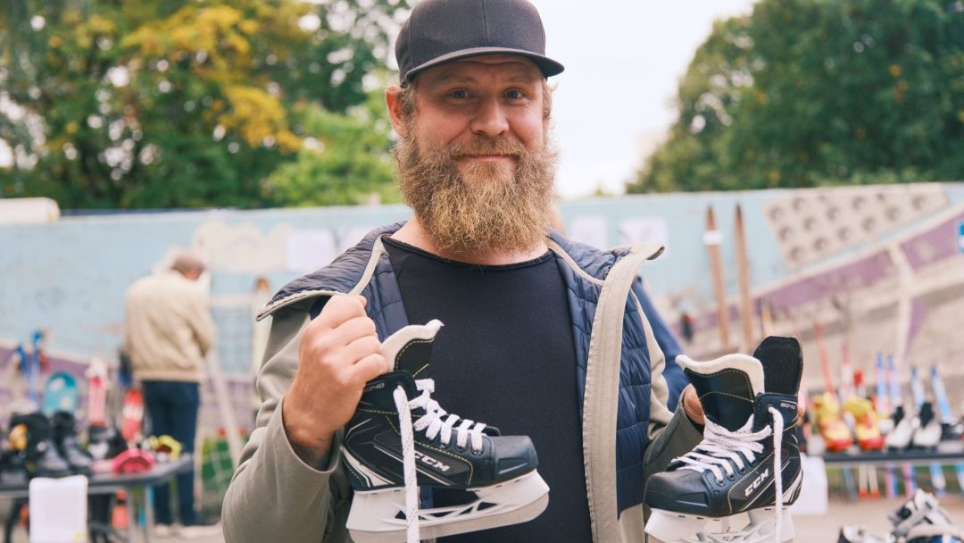 En skjeggete mann griper skøytene sine på en travel loppis, og den livlige markedsscenen visker ut til et livlig bakteppe.