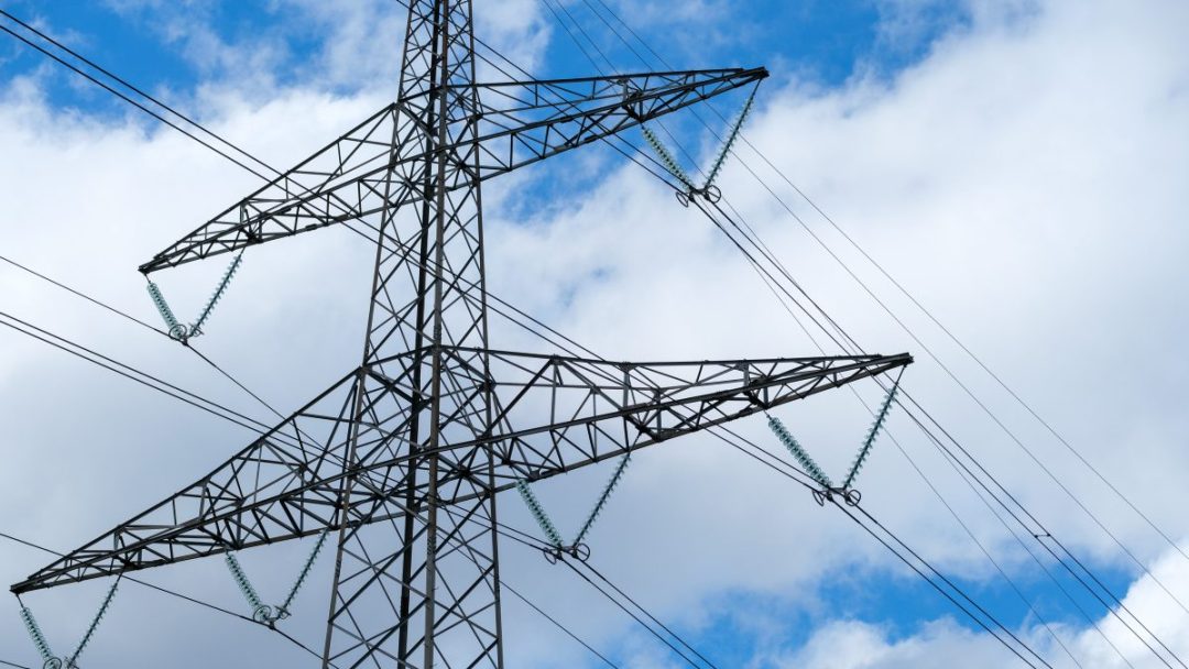 Et høyt elektrisk overføringstårn, innrammet av et bakteppe av blå himmel og skyer, står som en påminnelse om strømsparetips – energisparende tips – som kan hjelpe oss å utnytte kraften mer effektivt.