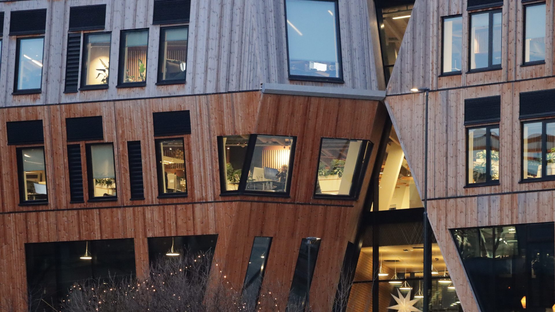 Vertikal Nydalen-bygget er et trekledd, moderne vidunder med store, skråstilte vinduer. Gjennom glassrutene antyder det opplyste interiøret et varmt opphold, mens stjernedekorasjoner pryder rommene innenfor.