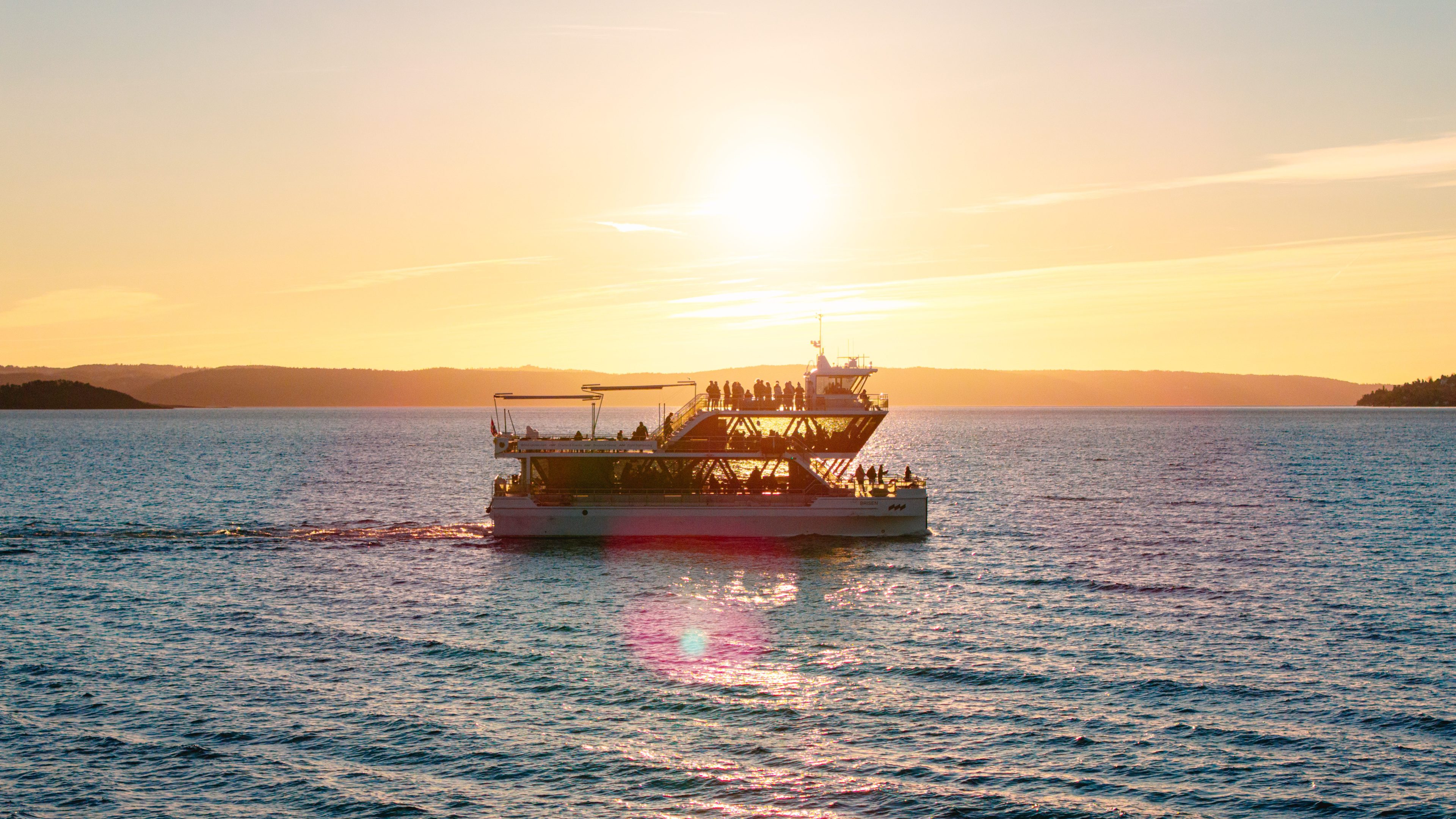 Ferje på sjøen med solnedgang bak