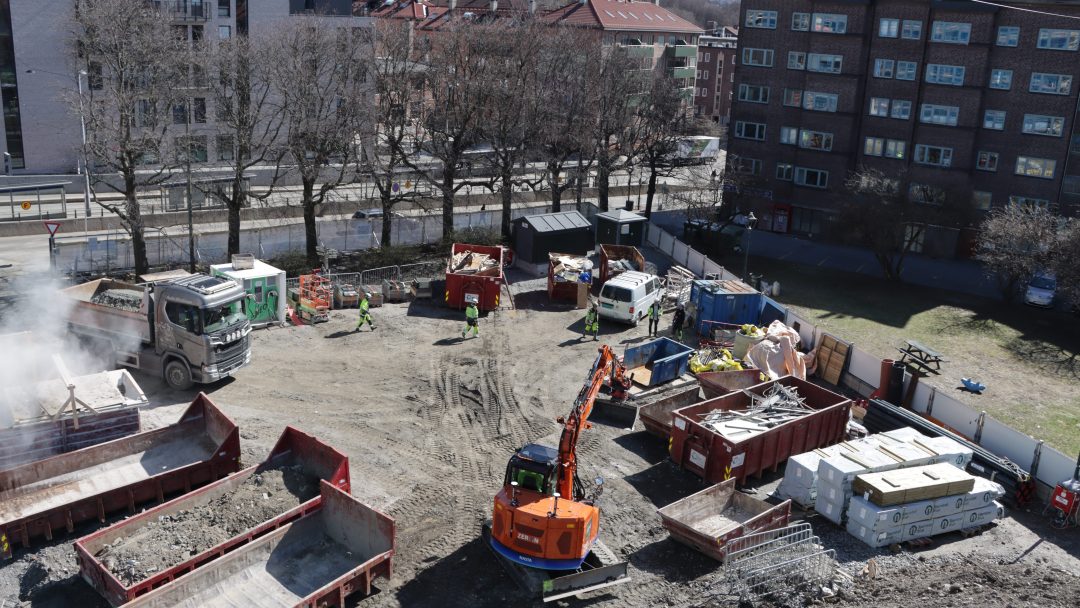 Anleggsplass med gravemaskiner og containere.