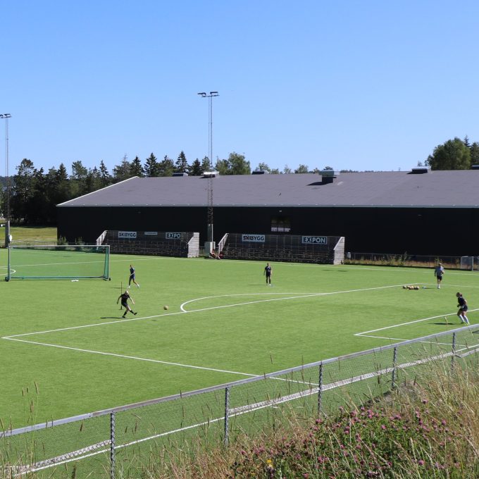 fotballspillere trener på kunstgressbane i sollys og blå himmel
