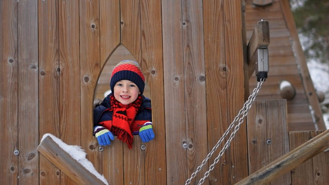barn på lekeplass som titter gjennom et hull