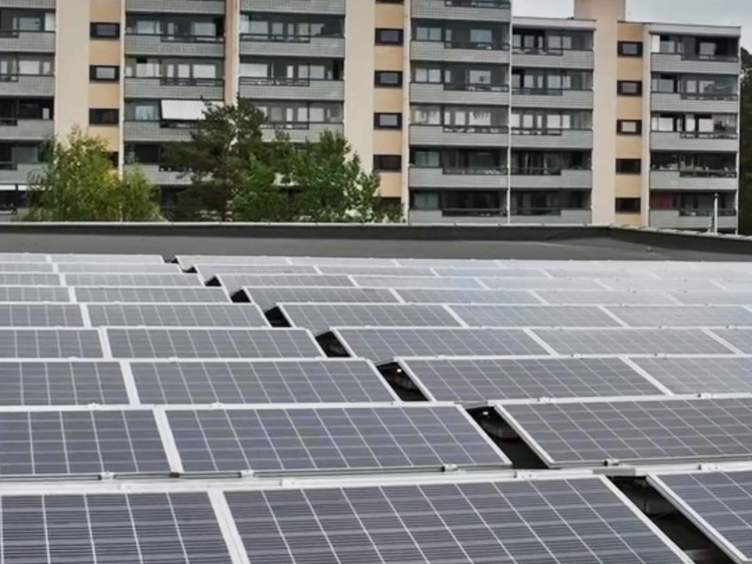 Solcellepaneler på et hustak med leilighetsbygg i bakgrunnen, viser Oslos satsing på bærekraft gjennom KlimaOslo-tiltak under overskyet himmel.